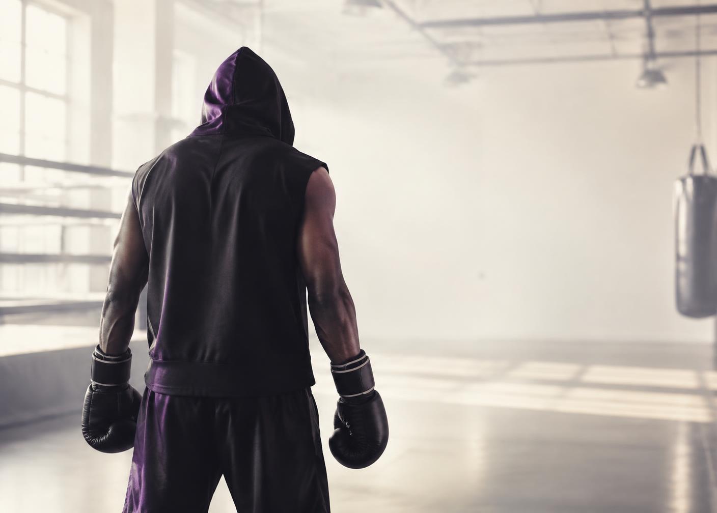 Boxer in a hooded top standing in a bright training gym